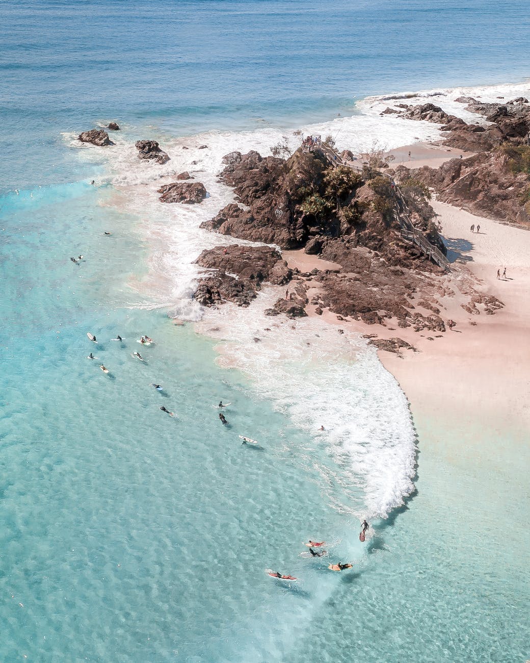 unrecognizable tourists swimming in ocean near rocky coast